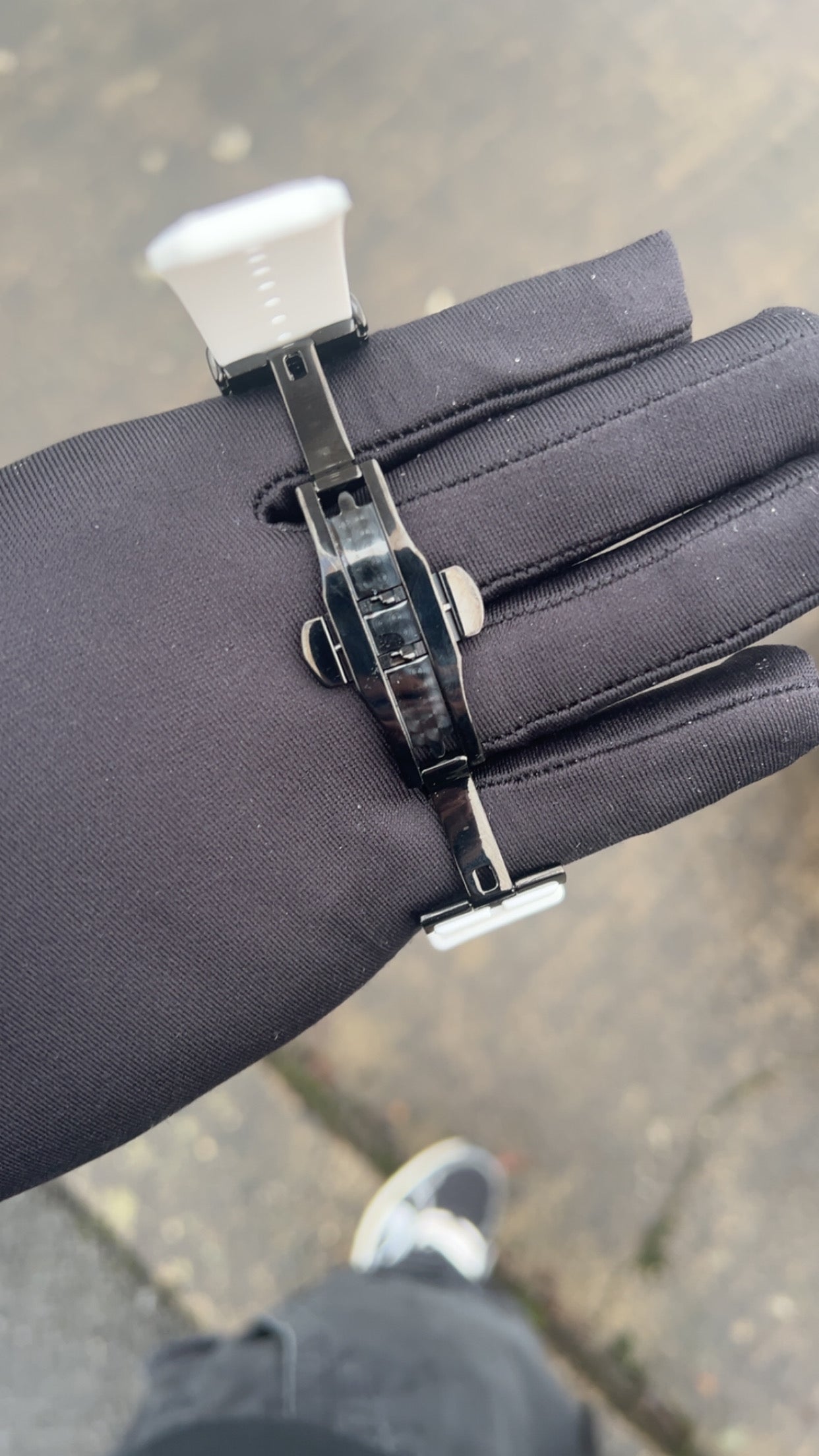 Black glove with a metal clip on a blurred pavement background