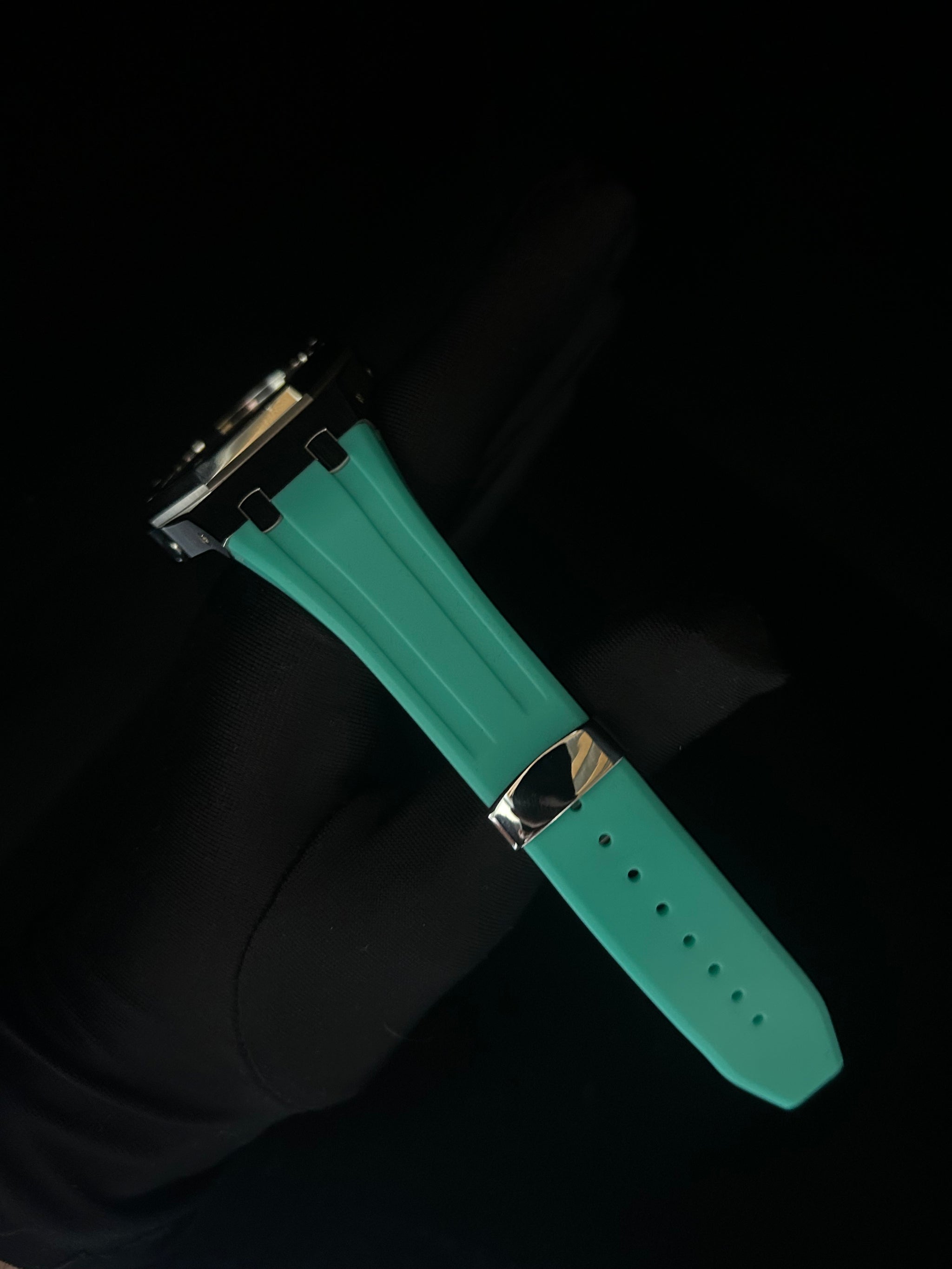 Green watch strap with silver clasp on a black background
