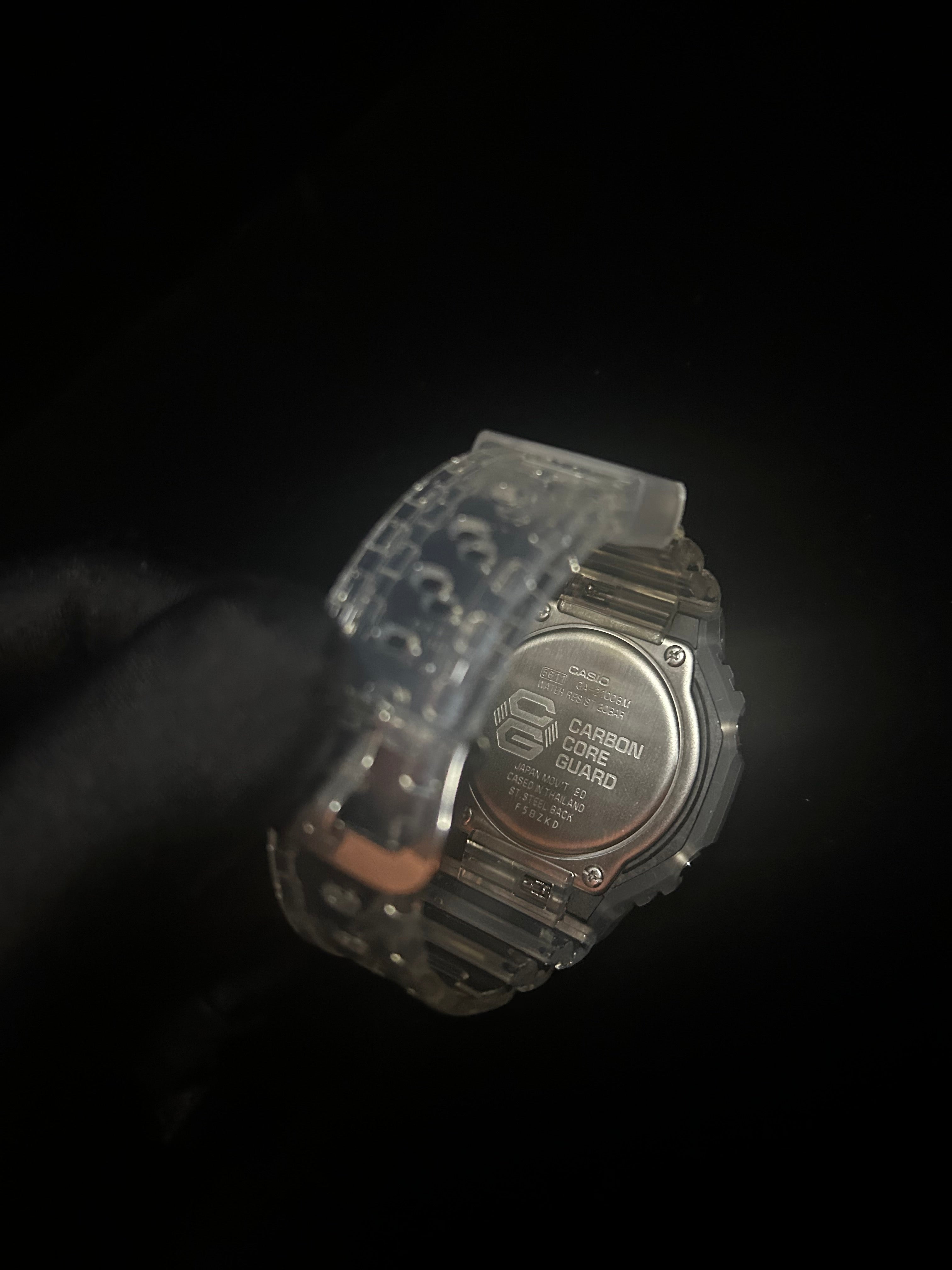 Digital watch held by a hand against a dark background
