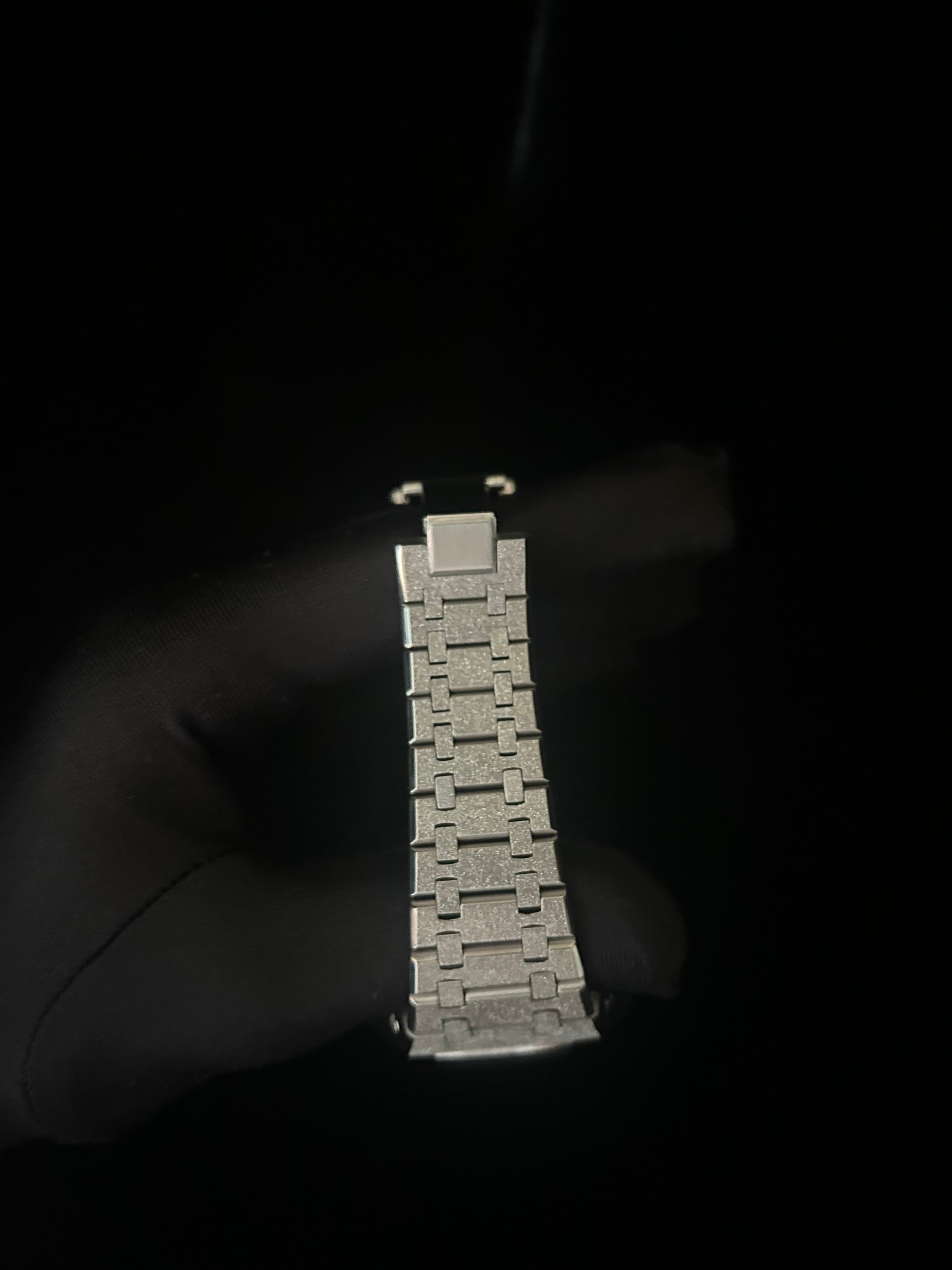 Metallic watch strap on a dark background