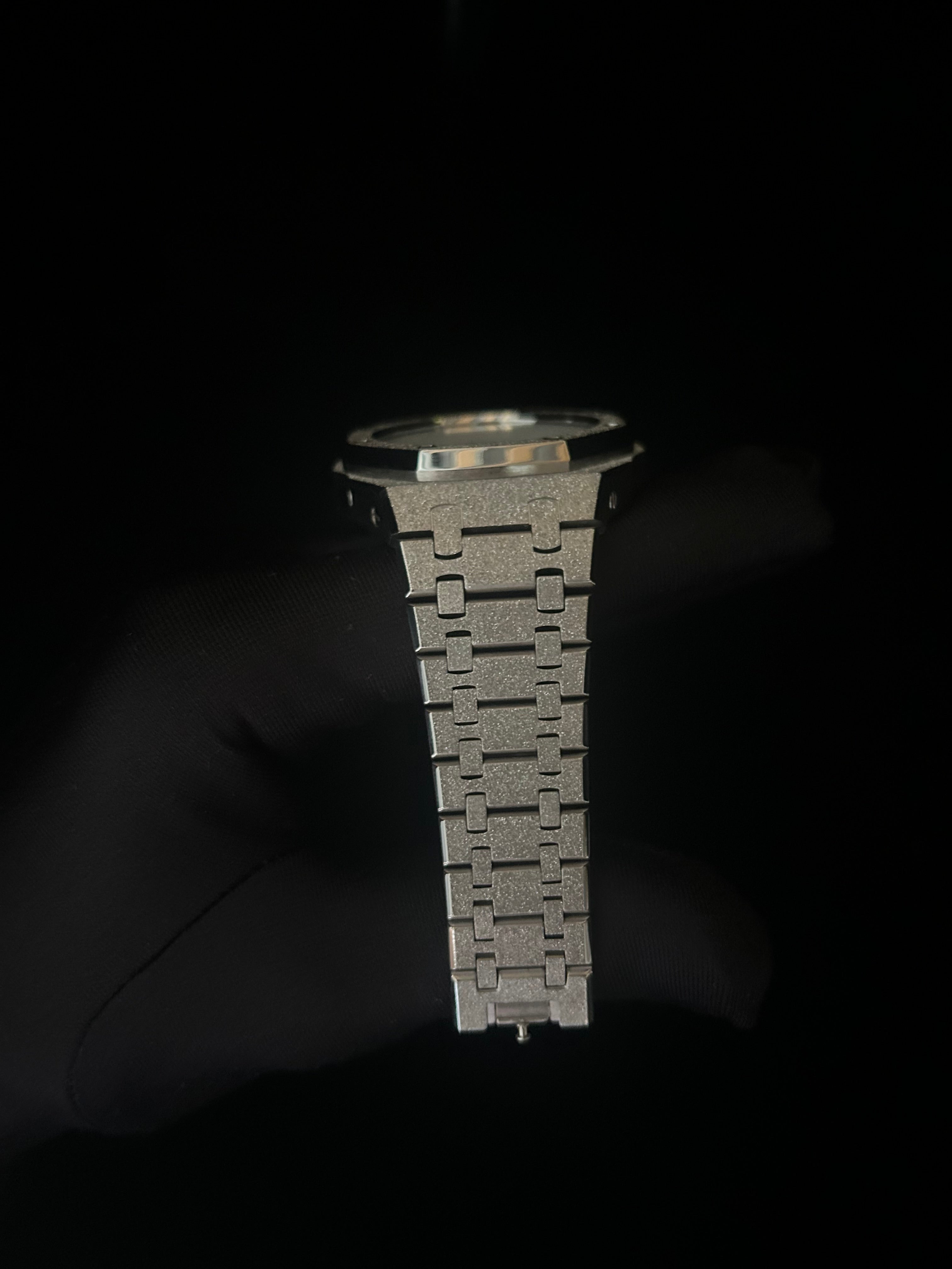 Metallic watch strap on a dark background