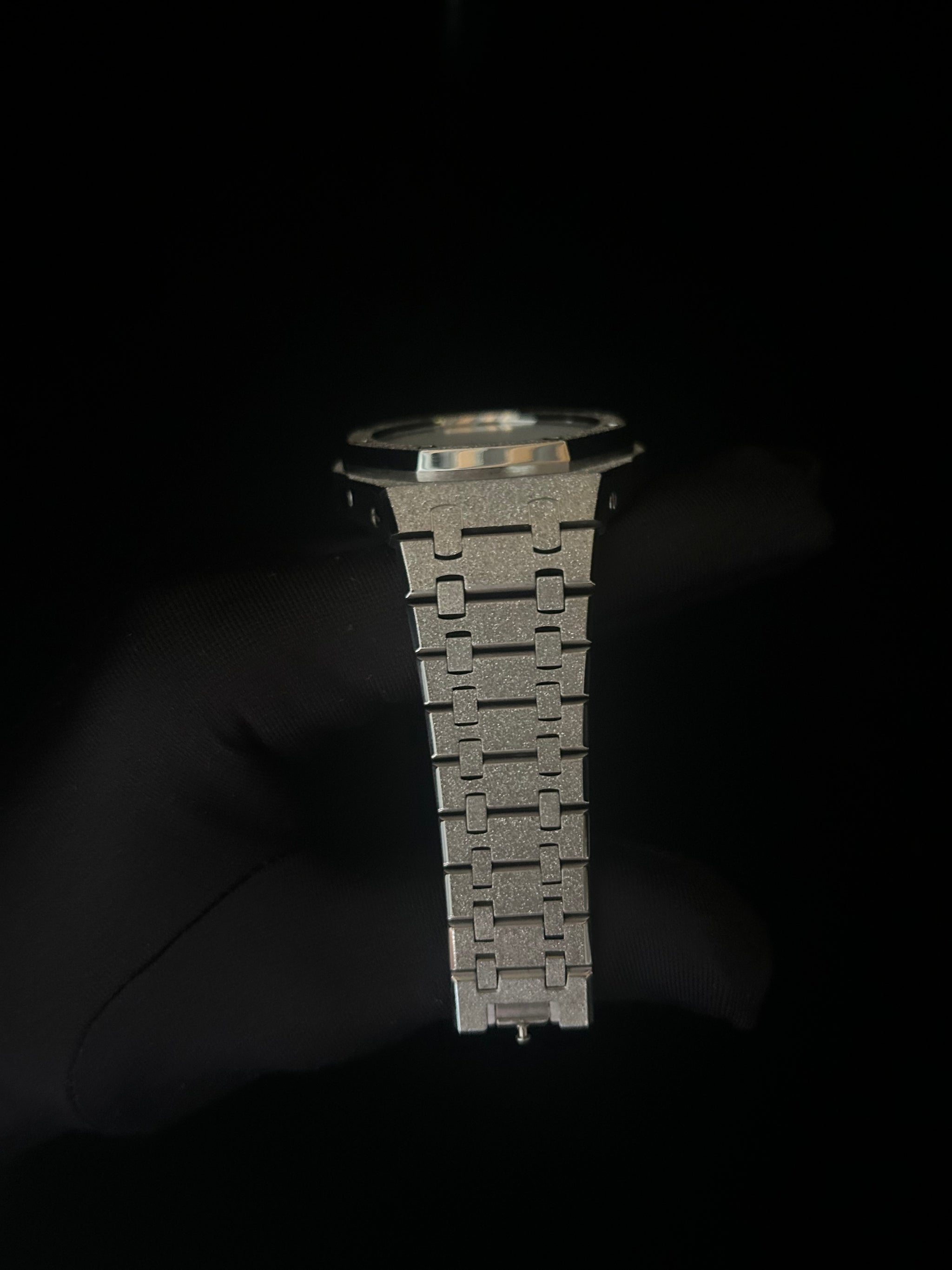 Metallic watch strap on a dark background