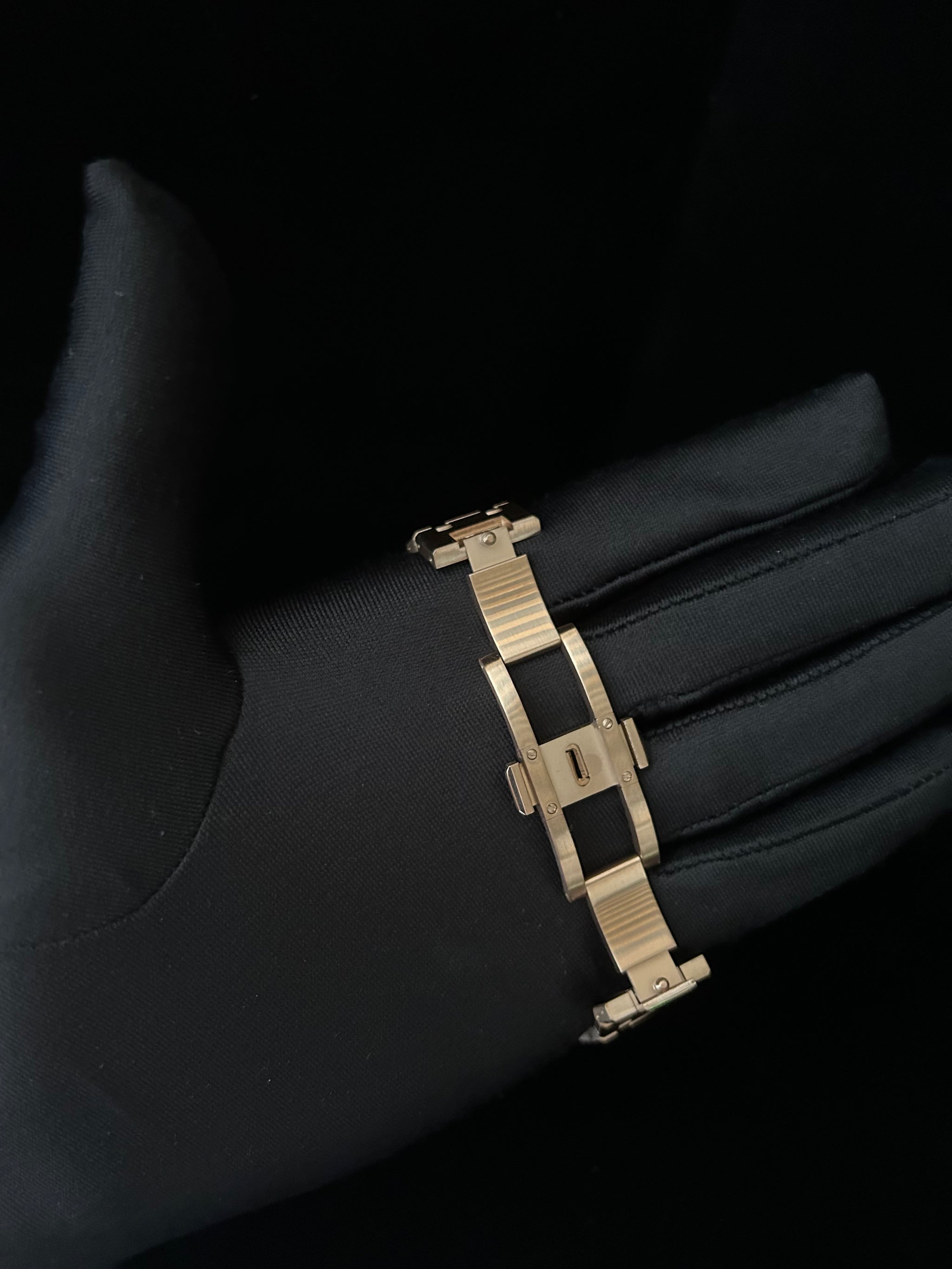 Rose Gold bracelet on a black gloved hand against a dark background
