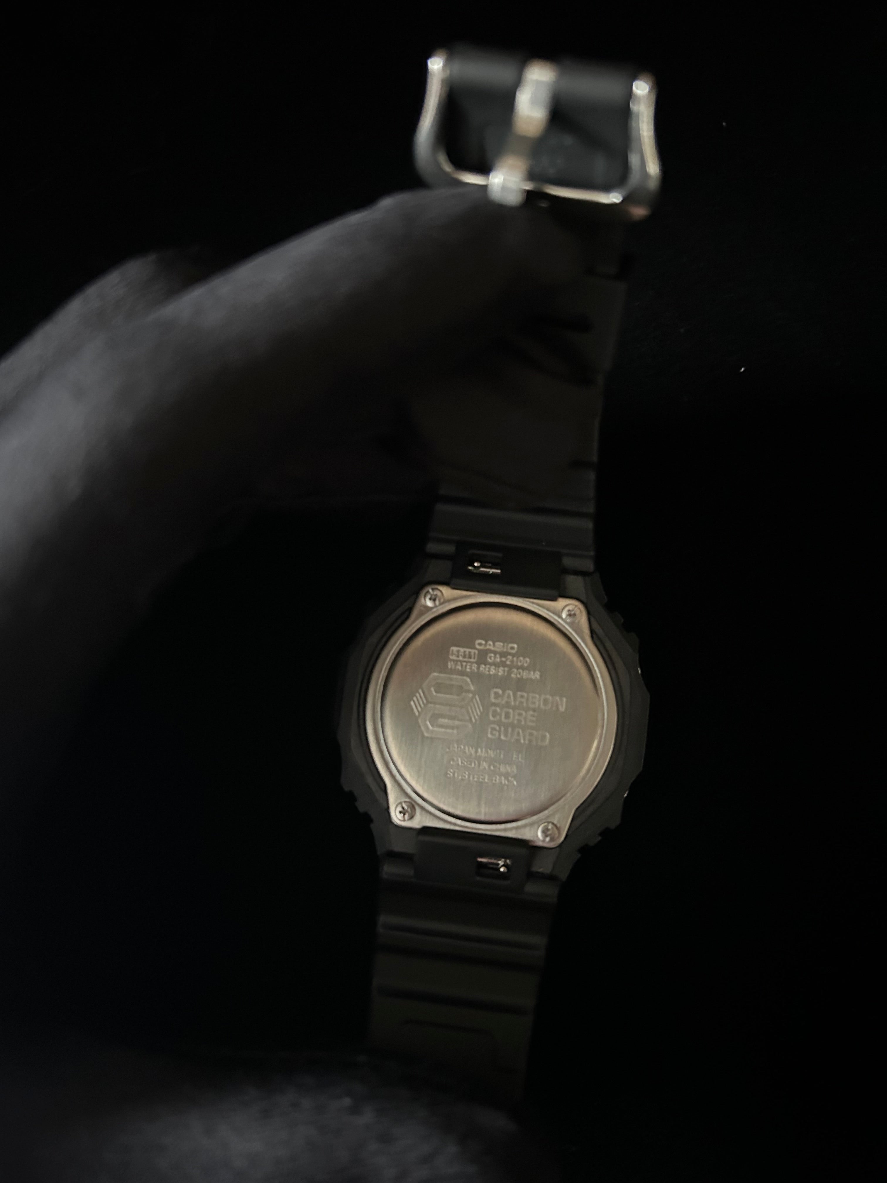 Black digital watch with metallic caseback on a black background