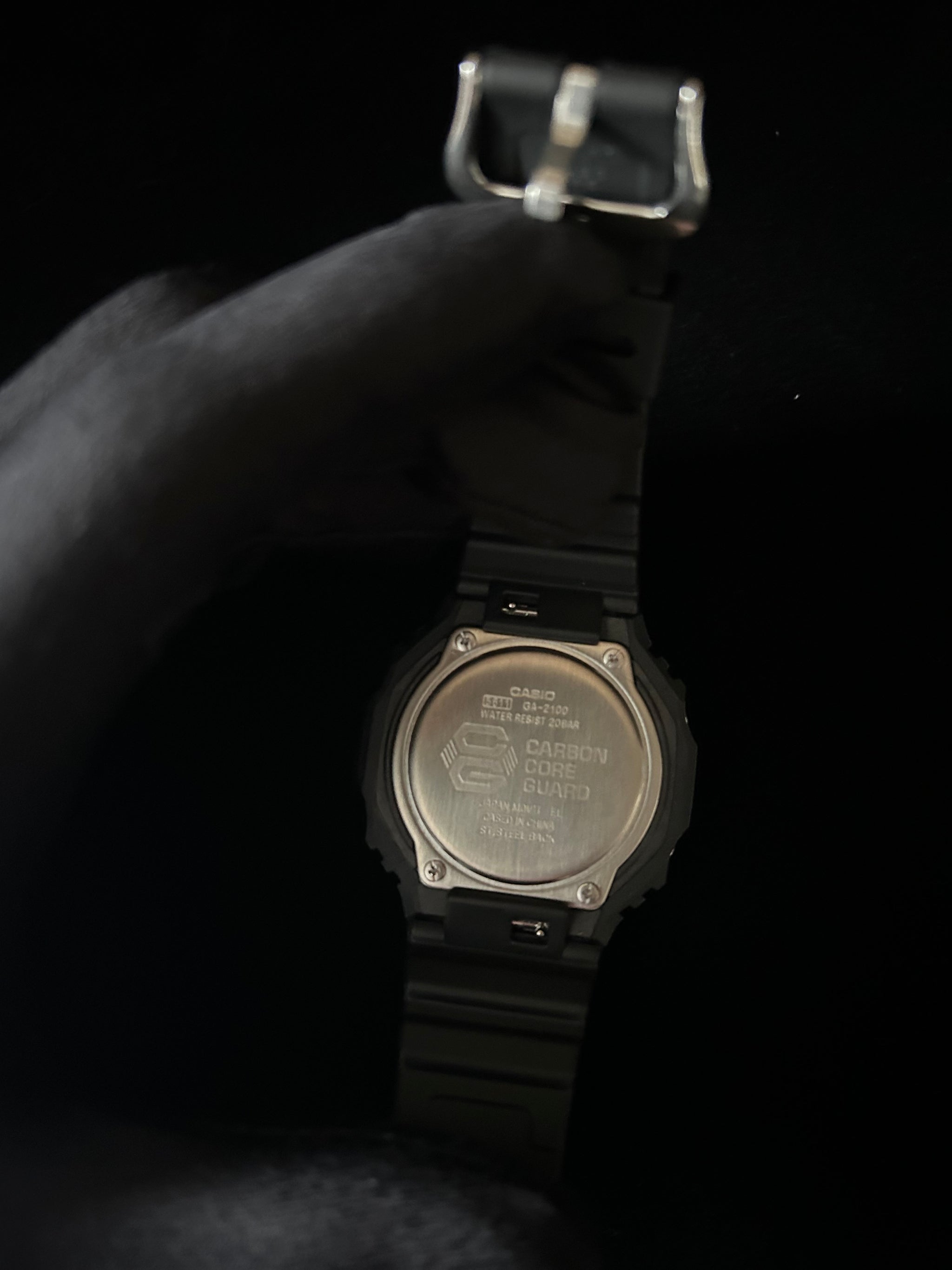 Black digital watch with metallic caseback on a black background